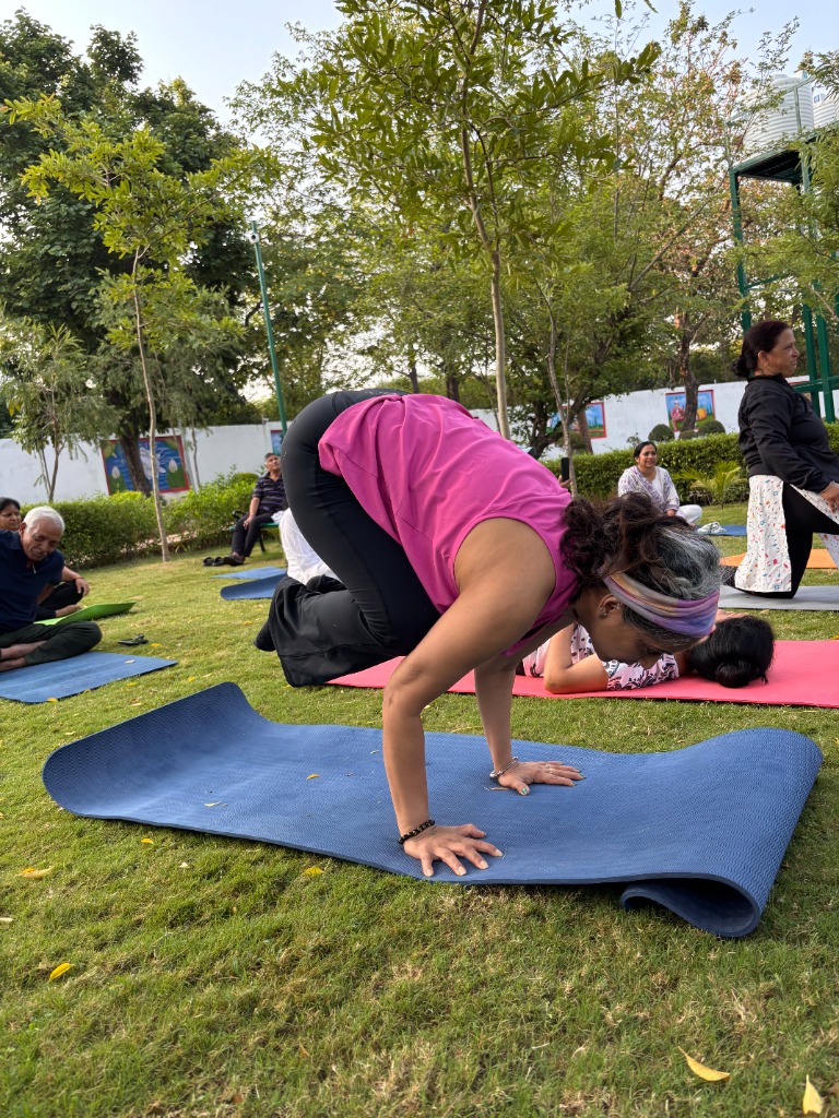 Practitioner practicing Crow pose (Bakasana variation) in a park