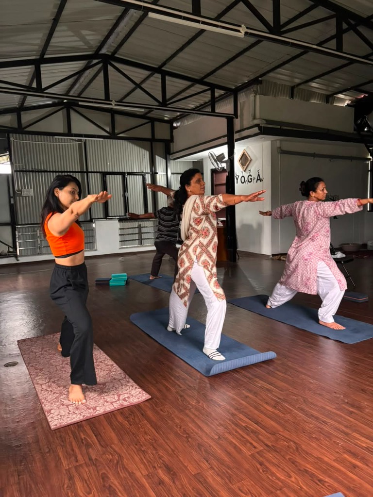 Group class practicing Warrior pose in the studio